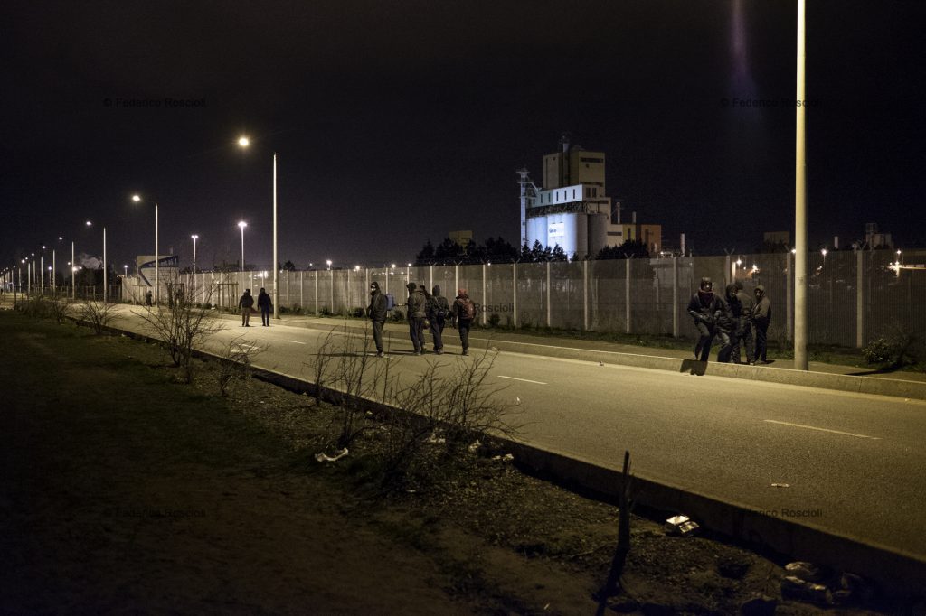 Calais, France. February 28, 2016. During evenings and nights migrants walk from the camp to the train station or the truck parking in order to "try it", meaning try to reach the UK. The Calais Jungle Camp for migrants, in Calais, France, dates January 2015, it is now the biggest refugee camp in Europe, hosting around 3700 migrants from all over the world. The people hosted in the camp are willing to reach the UK due to the lack of job opportunities in the rest of Europe.