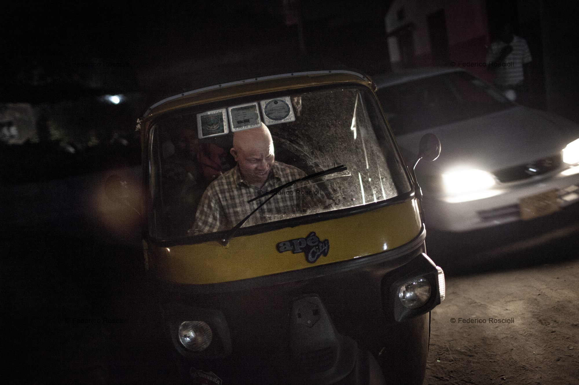 Dar es Salaam, Tanzania, July 29, 2014 - Redman driving his bajaj in Dar es Salaam, Tanzania. Despite albinism, he has been a driver for 9 years, the last 3 on a bajaj. A Bajaj is a three-wheel taxi, perfect to move in Dar traffic. Being covered on the top, it is also a shield from the sun for an albino. Redman also has to fight against discrimination to be able to work. He has to pay a person to pick up the bajaj from the owner every day, as the owner does not want albino drivers, not trusting their sight.